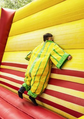 The boy in colorful plastic dress in the bouncy castle clipart