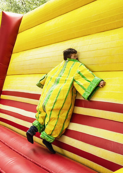 The boy in colorful plastic dress in the bouncy castle