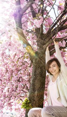 Mutlu genç kadın yansıyan s ile sakura ağacı üzerinde asılı