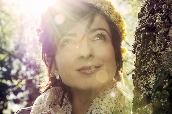 Romantische jongedame met krans van paardebloemen op de kop in su — Stockfoto