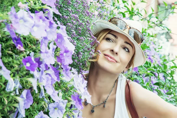 Unga kaukasiska kvinna poserar med vackra violetta blommor — Stockfoto