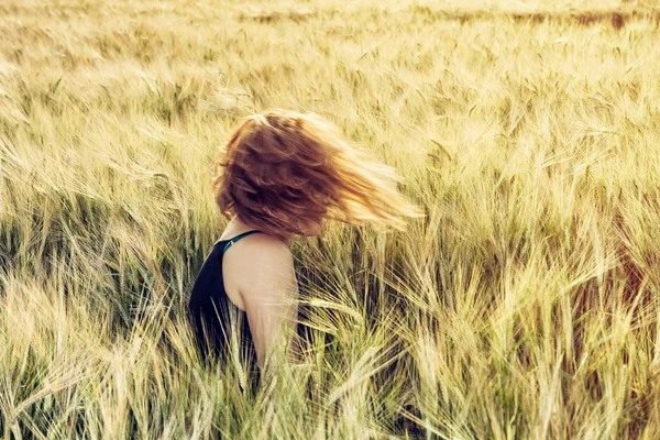 Jonge Kaukasische vrouw gooit met haar haren in een tarweveld — Stockfoto
