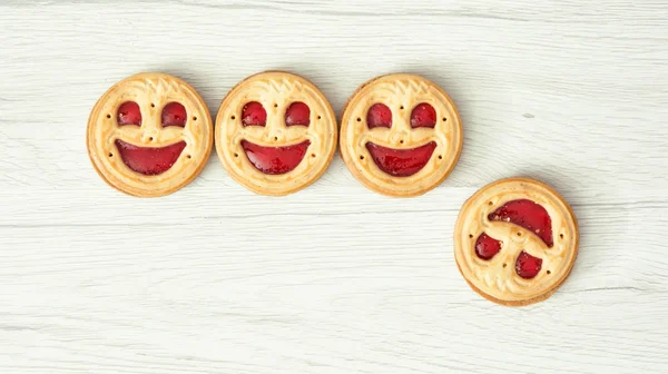 Four round biscuits smiling faces, one of them falls down — Stock Photo, Image