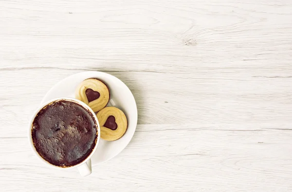Kopje zwarte koffie met twee jam koekjes in de vorm van hart — Stockfoto