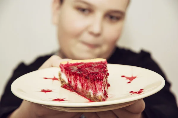 Junger fröhlicher Junge mit dem Stück Käsekuchen mit Himbeeren, — Stockfoto