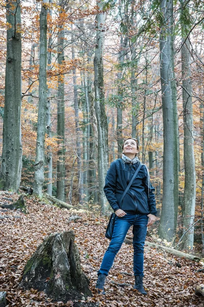 Young caucasian tourist woman is looking around in autumn forest — Stock Photo, Image