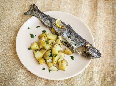 Tabakta patates ve limon ile lezzetli ızgara alabalık