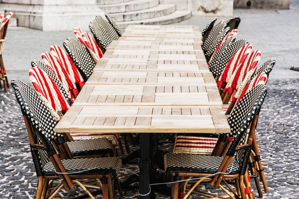 Proutěné židle a kamenné tabulky v zahradní restauraci — Stock fotografie