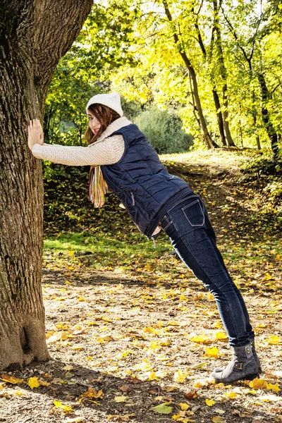 Молодая позитивная женщина позирует с деревом и расслабляется к осени — стоковое фото
