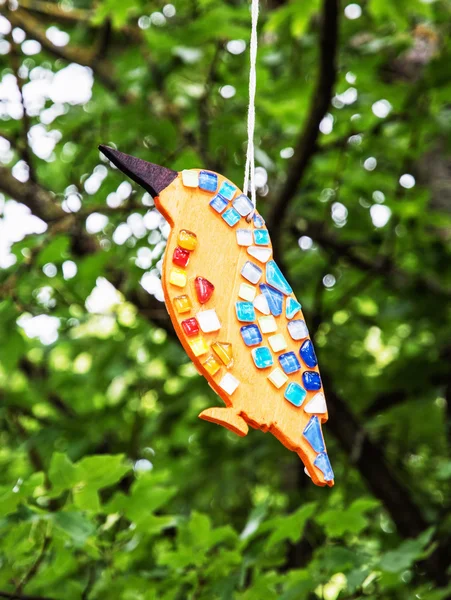 Ceramic decoration in the bird shape hanging on the green tree — Stock Photo, Image