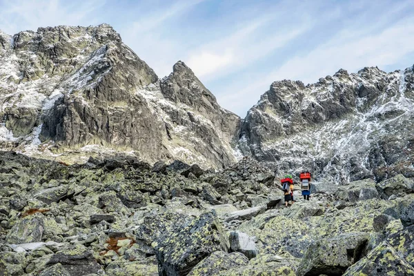 Mountain carriers walking to the mountain cottage under the Rysy peak, High Tatras mountains, Slovak republic. Hiking theme.