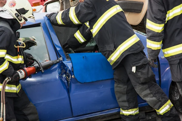 Firemen opening the car doors with hydraulic scissors — Stock Photo, Image