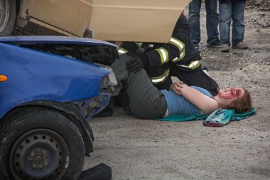 Firefighters saving the bleeding woman from a crashed car clipart