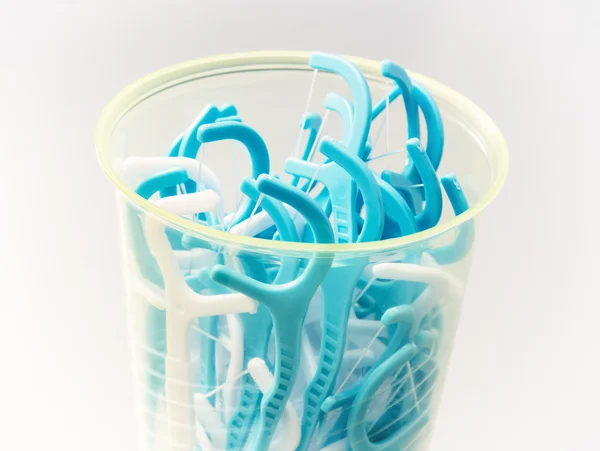 Blue dental floss sticks in plastic cup — Stock Photo, Image