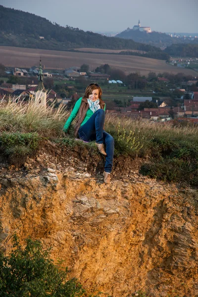 Jonge vrouw zit op een kalksteen rots door de zon instelling — Stockfoto