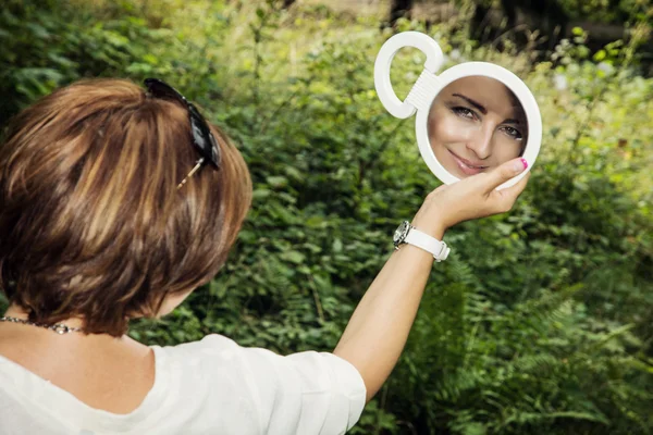 Mladá brunetka se dívá do zrcadla — Stock fotografie