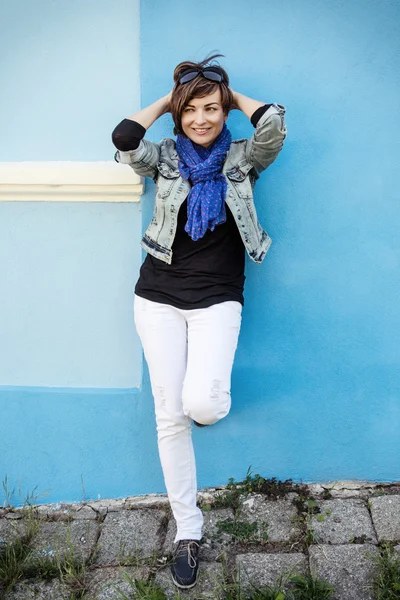 Mulher positiva bonita posando na frente da parede azul — Fotografia de Stock