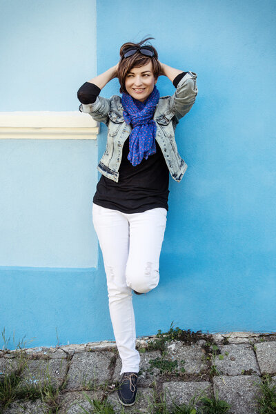 Beautiful positive woman posing in front of the blue wall