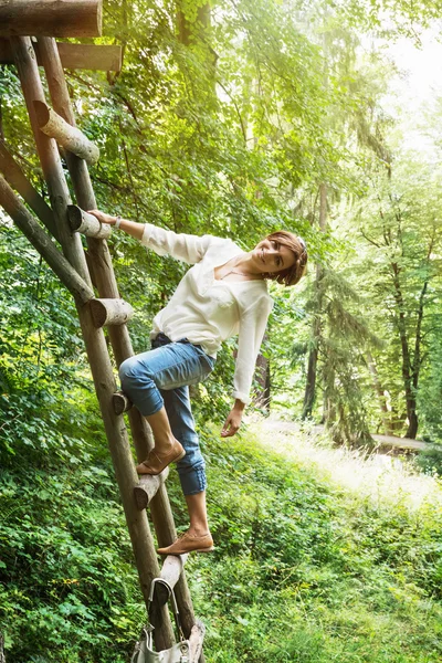 Young caucasian brunette posing on the wooden ladder — Stock Photo, Image