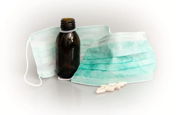 Two medical masks, pills and cough syrup bottle — Stock Photo, Image