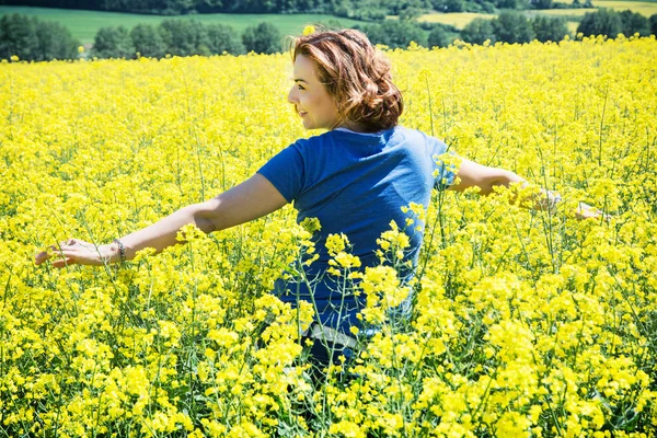 Young woman relaxing in rapeseed field — Stock Photo, Image