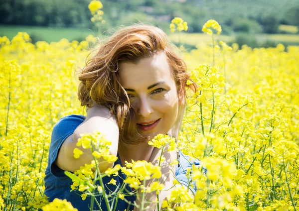 Mooie jonge brunette in koolzaad veld — Stockfoto