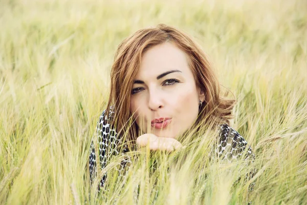 Ung kvinna skicka en söt kyss i fältet vete — Stockfoto