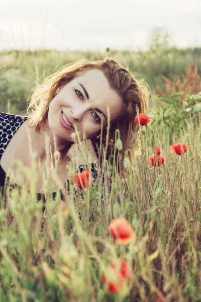 Beautiful woman is smiling and posing in poppy flowers field — Stok fotoğraf