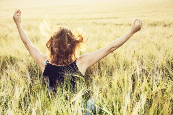 Junge Frau winkt der Sonne im Sommer auf dem Feld zu — Stockfoto