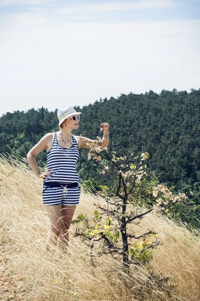 Mujer bonita de pie junto al pequeño árbol y tocándolo — Foto de Stock