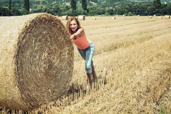 Femme souriante poussant la meule de foin et s'amusant par la récolte — Photo