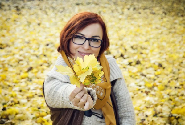 Jeune rousse femme aux feuilles d'automne jaunes — Photo