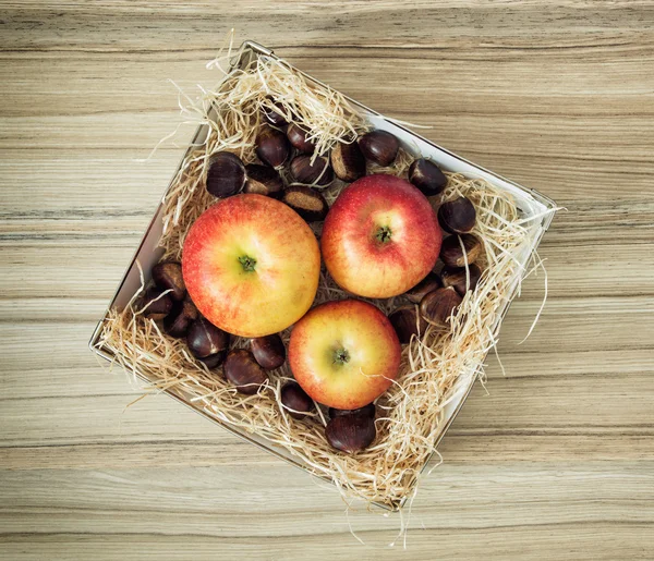 Tres manzanas y castañas en la caja — Foto de Stock