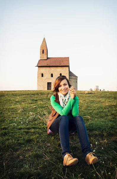 Young woman is sitting in front of the church — Stock Photo, Image