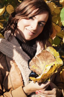 Sonbahar renkli yaprakları ile oynayan genç kadın