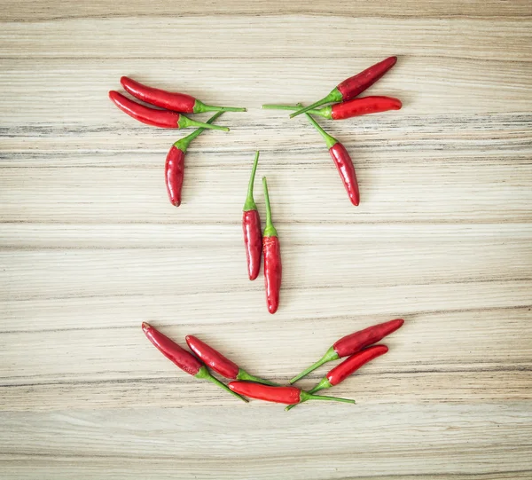 Face made of chilli peppers on the wooden board — Stock Photo, Image
