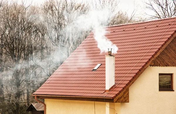 Red roof and smoking chimney — Stock Photo, Image