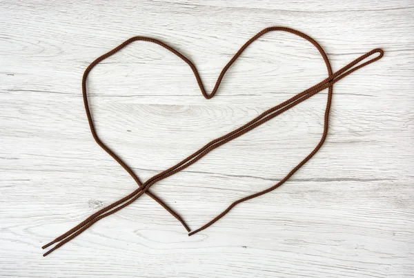 Brown shoelaces shaped in the heart on the wooden background, Va — Stock Photo, Image