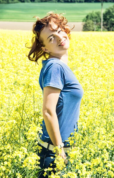 Glückliche junge Frau posiert im Rapsfeld — Stockfoto