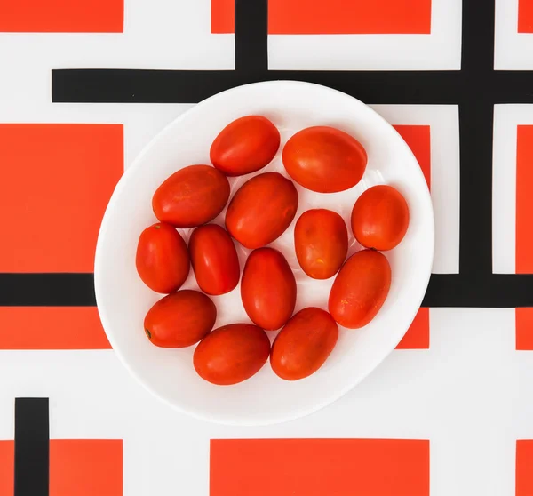 Kiraz domates beyaz plaka ve kırmızı geometrik modern backgrou — Stok fotoğraf