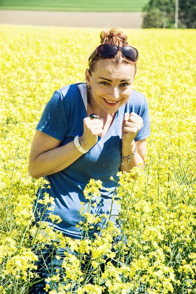 Mujer joven en el campo de colza tiene miedo de los insectos — Foto de Stock