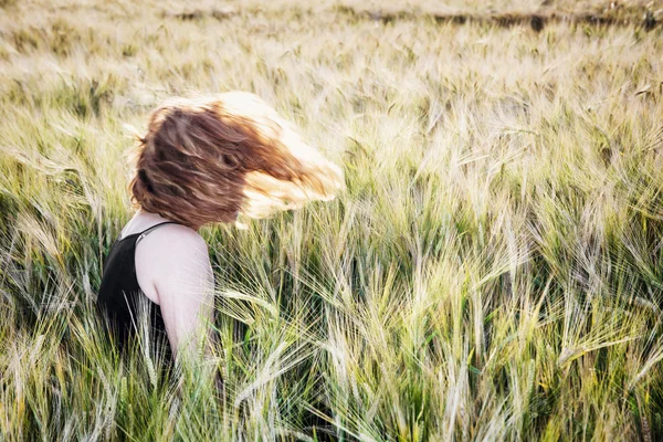 Junge Frau wirft mit Haaren in Weizenfeld — Stockfoto