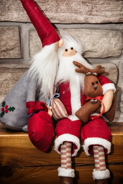 Dois Pai Natal feitos de pano com renas sentadas sobre a pedra fi — Fotografia de Stock