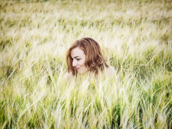 Jonge lachende vrouw is verborgen in het tarweveld — Stockfoto