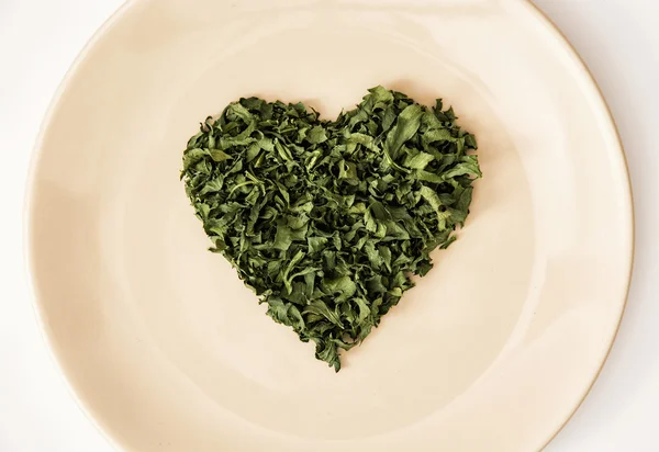 Herzform aus getrockneter Petersilie auf dem Teller, Valentinstag — Stockfoto