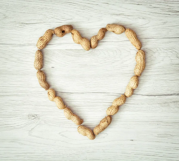 Heart of the peanuts on the wooden background, symbol of lovers — Stock Photo, Image