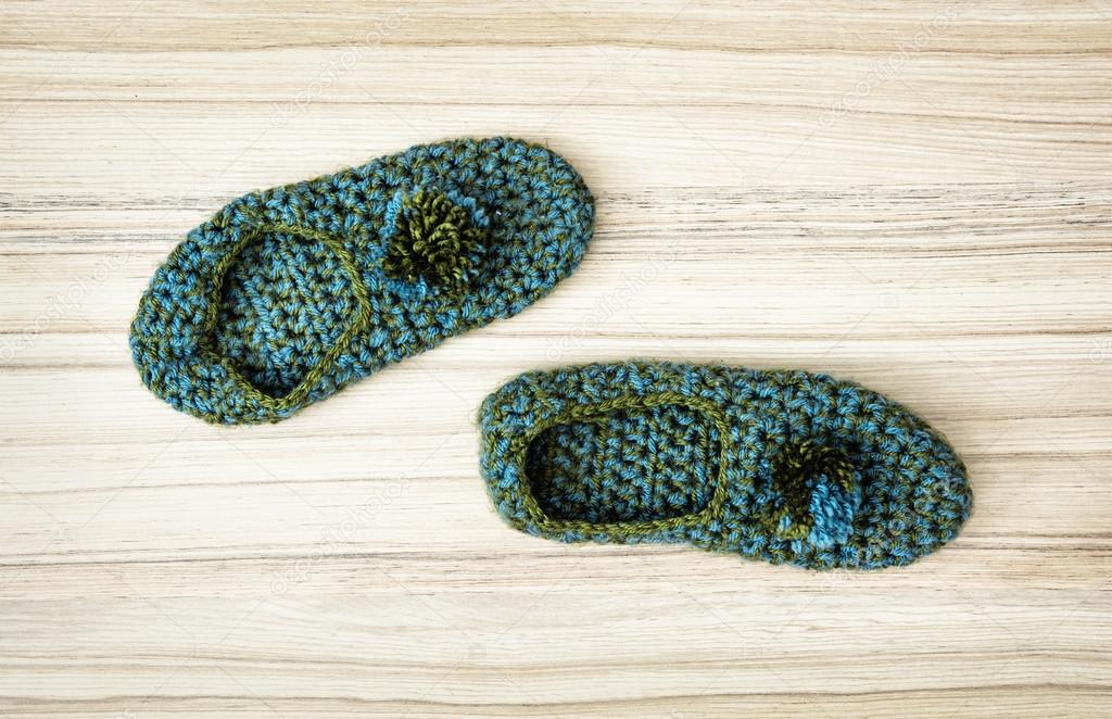 Beauty knitted slippers on the wooden background