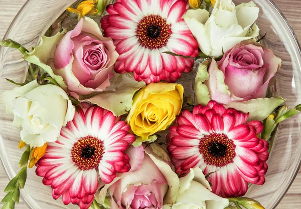 Güller ve gerberalar çiçekler cam kase su ile tatil — Stok fotoğraf