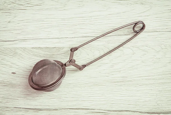 Colador de té sobre fondo de madera, retro tonificado — Foto de Stock