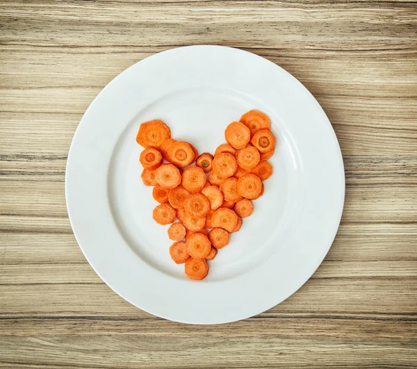 Sliced carrots in the heart shape on the white plate, Valentine' — Stock Photo, Image